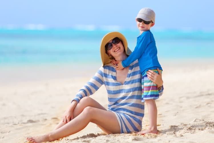 mom and child on a sunny beach wearing hats
