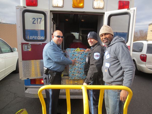 Police Officer and two other volunteers putting a box of toys into an ambulance