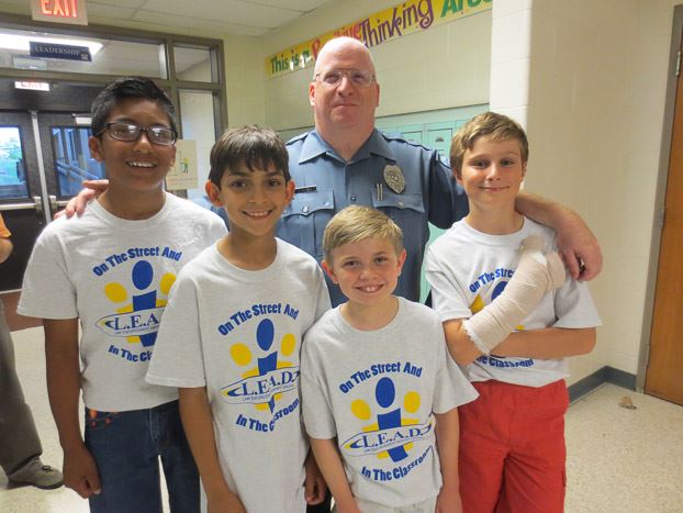 Officer standing behind four children, smiling